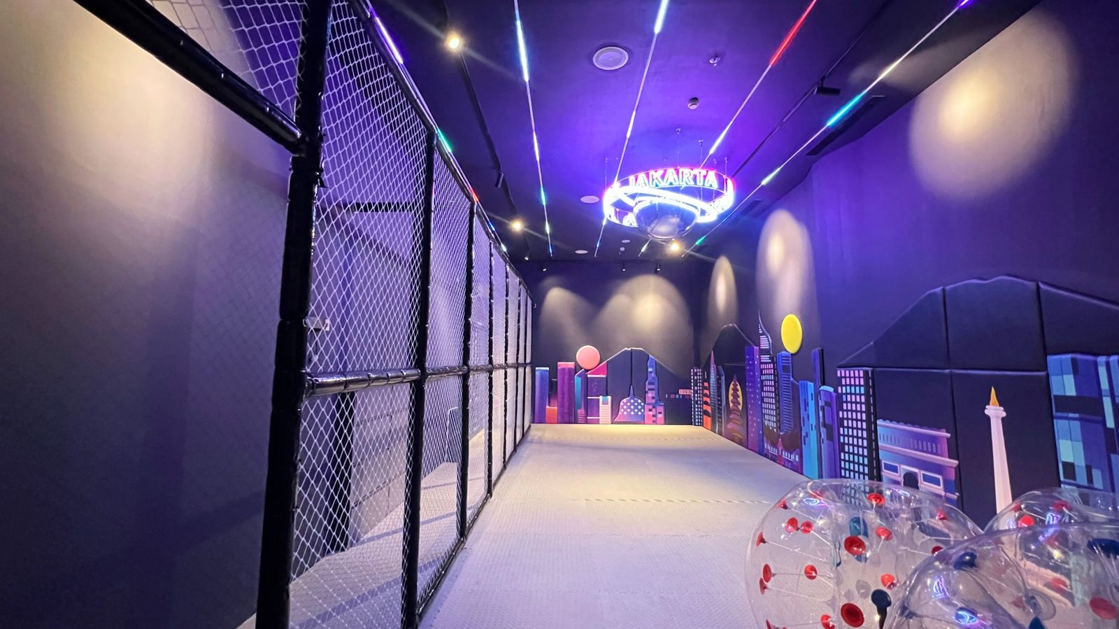 Indoor bumper ball arena with neon Jakarta skyline mural