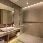 Modern hotel bathroom with a round mirror and walk-in shower