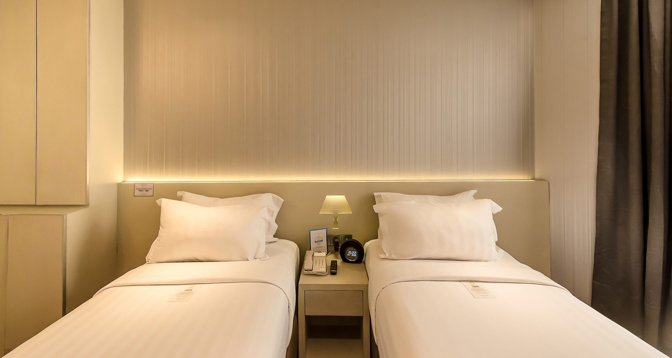Two twin beds in a well-lit, contemporary hotel room