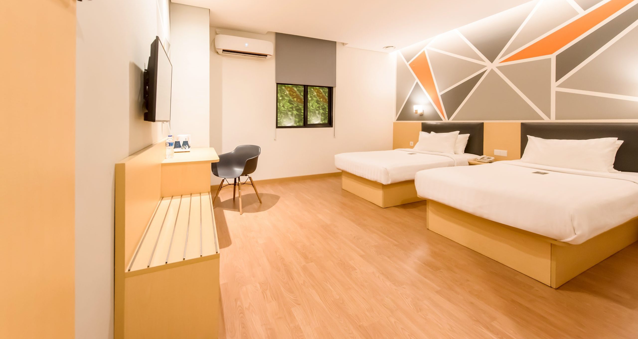 Two twin beds in a modern, sunlit hotel room