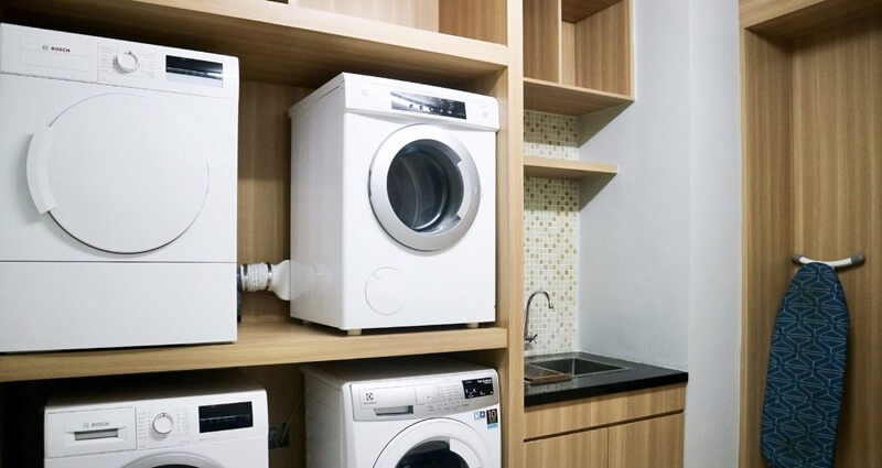 Hotel laundry room with stacked washers and dryers