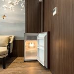 A black mini-refrigerator inside a wooden cabinet