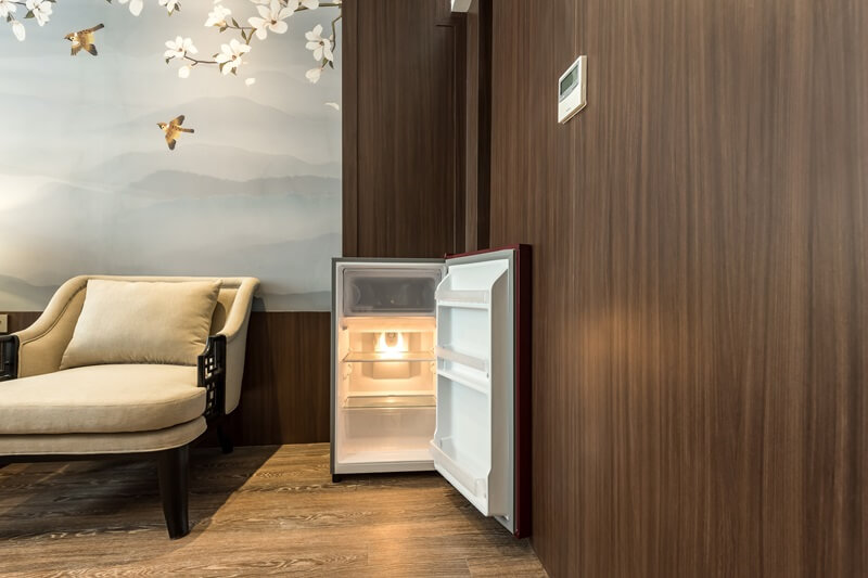 A black mini-refrigerator inside a wooden cabinet
