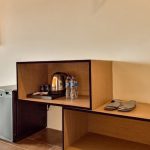 A modern hotel room corner with a bed and side table