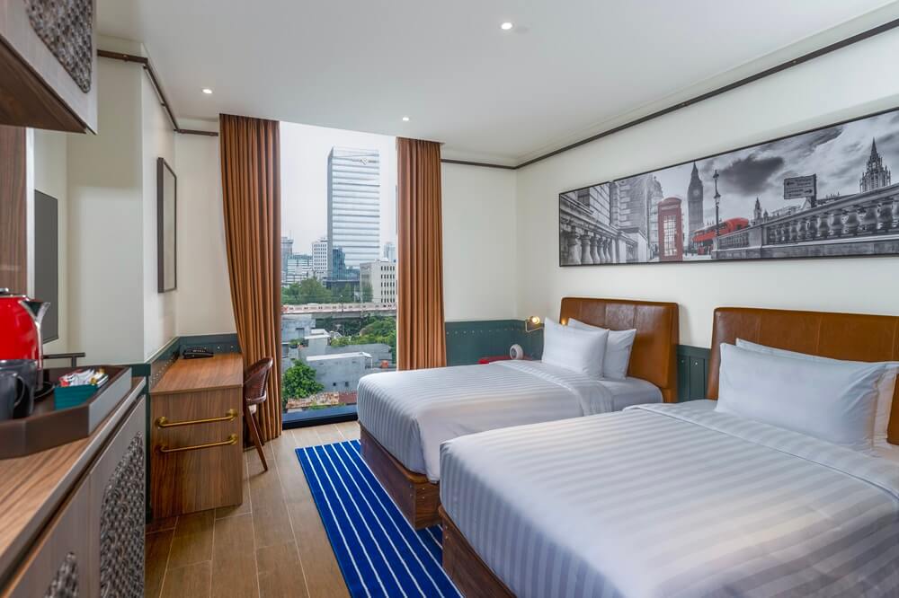 A twin bedroom with a city skyline view
