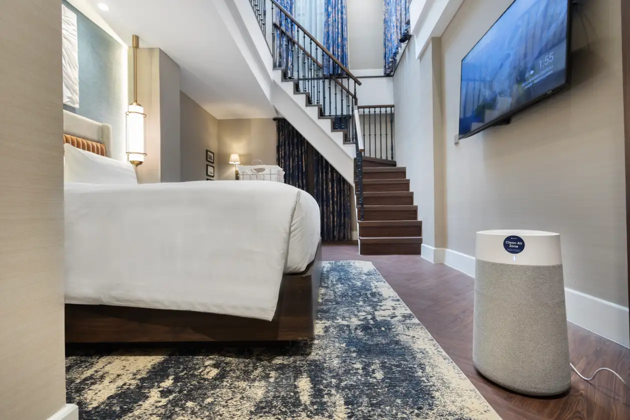Family duplex room with bed, stairs, and Blueair purifier